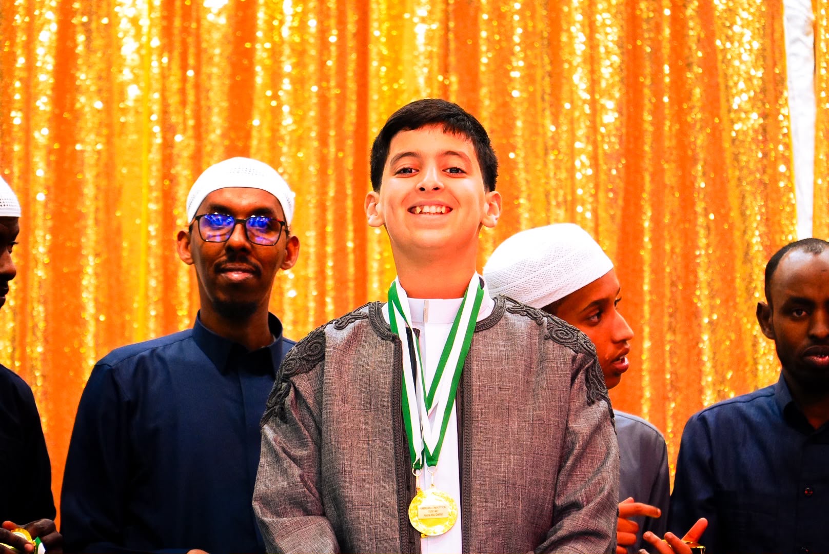 A young Al-Taqwa Academy student wearing a gold medal